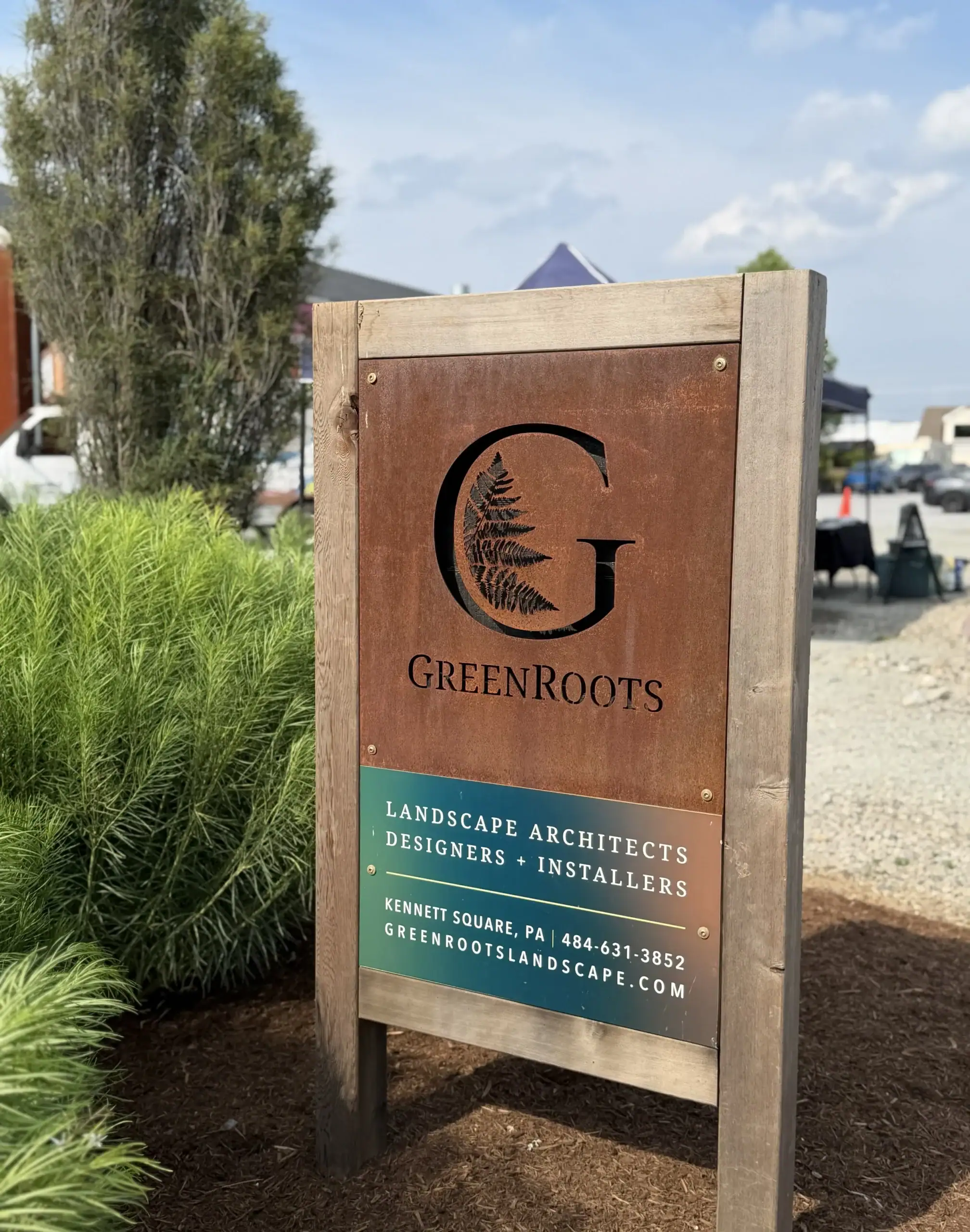 Corten steel and reclaimed wood landscape architecture firm signage with ornamental grass planting at base