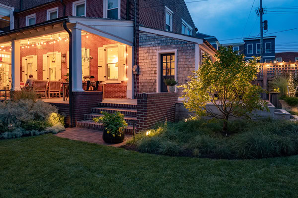 Professionally designed landscape lighting illuminating a custom residential home and outdoor living space at dusk.