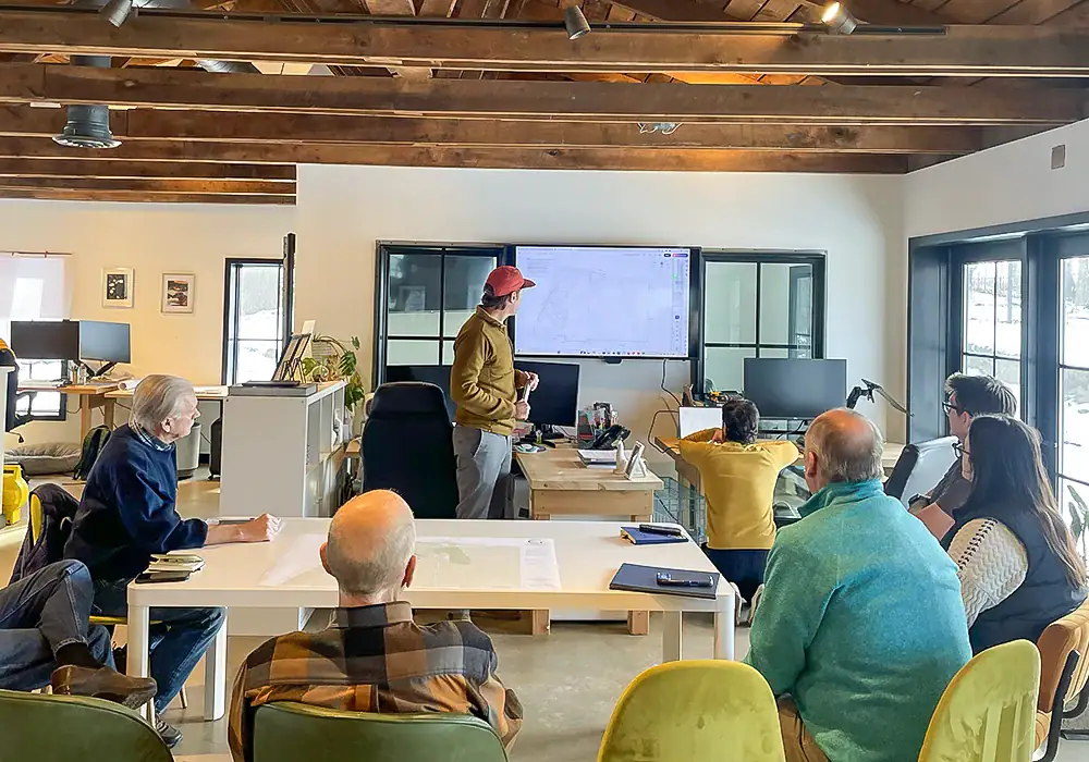 GreenRoots design team presenting a site plan on screen during a client consultation in the studio