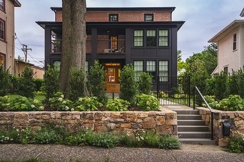 Dry-stacked stone retaining wall with hydrangeas, shrubs, and mixed perennials at the front entry of the Francis Hotel Kennett Square