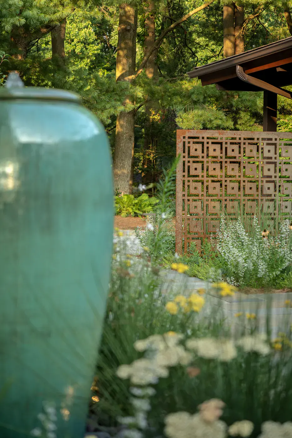 Glazed turquoise ceramic fountain urn beside a Corten steel screen, white calamint, yarrow, a white globe planter, and a bluestone path at a Wilmington DE home